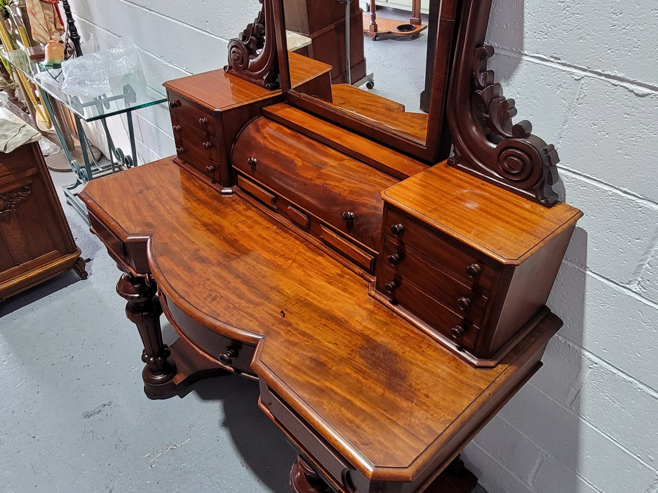 Beautiful Flame Mahogany Victorian duchess dressing table. Circa 1880 in date. It has a serpentine front outline and has an adjustable swing frame mirror. It is fitted with a central roll up storage section and then has three small drawers to either side, aswell as a central drawer in the middle of the serpentine front. It is in good original condition.
