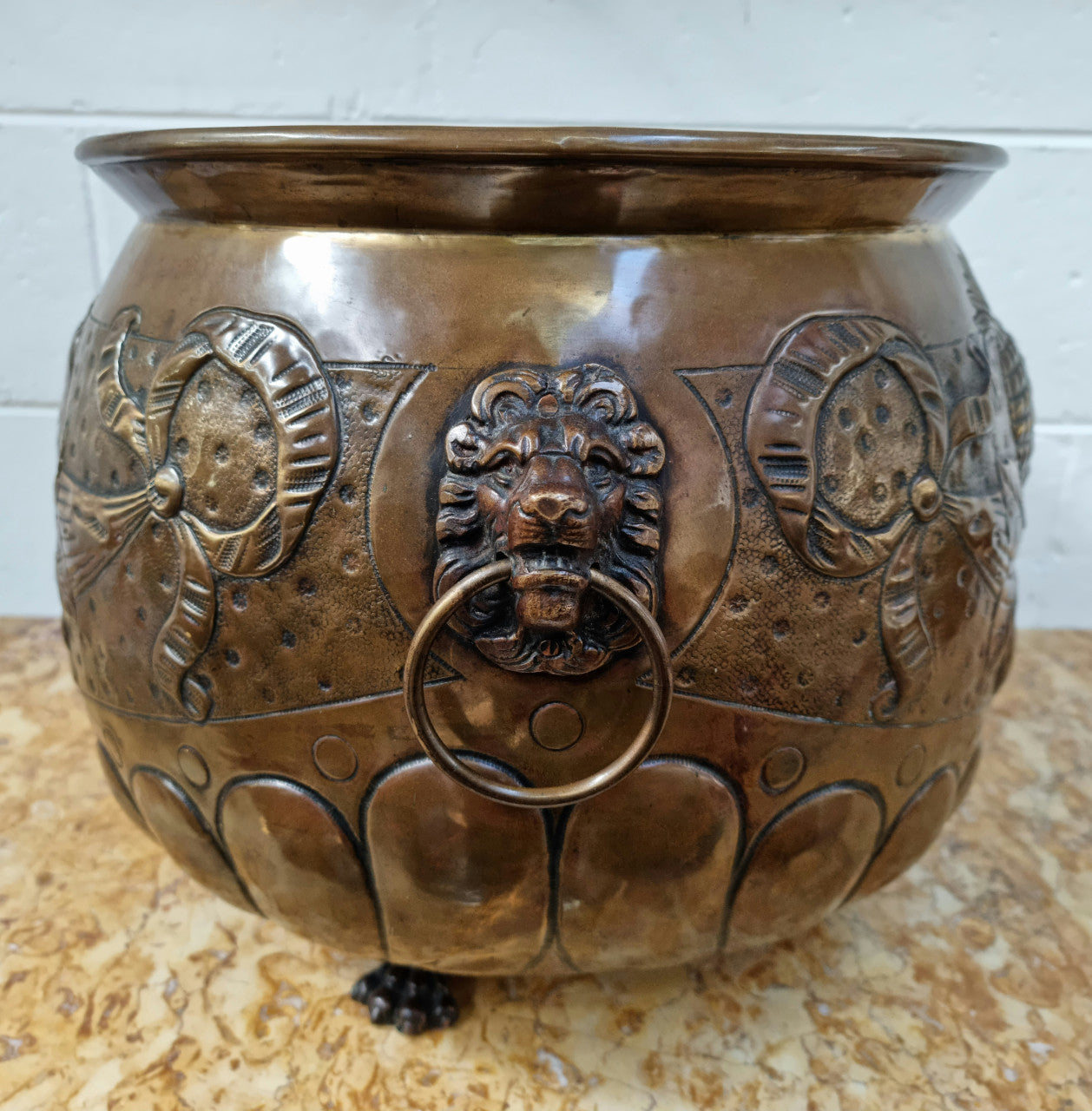 Antique large brass bronze coloured embossed Jardinière/planter with lovely details and lion heads for handles. It is in good original condition.