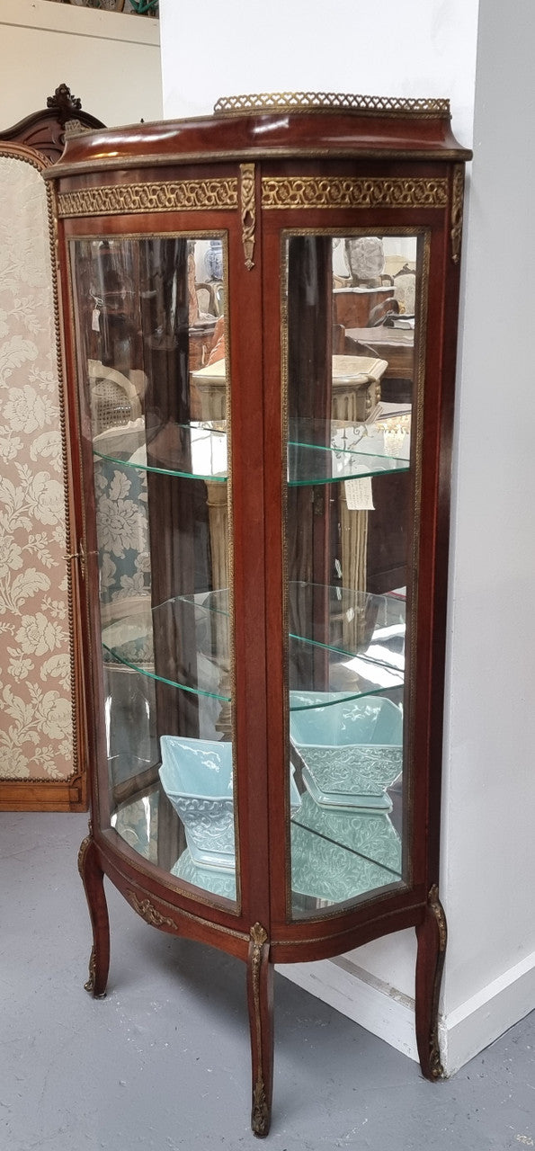 Beautiful French Louis XV style vitrine/ display cabinet with curved glass, gilt mounts, mirrored back and two glass shelves for your displays . It is in good original detailed condition.