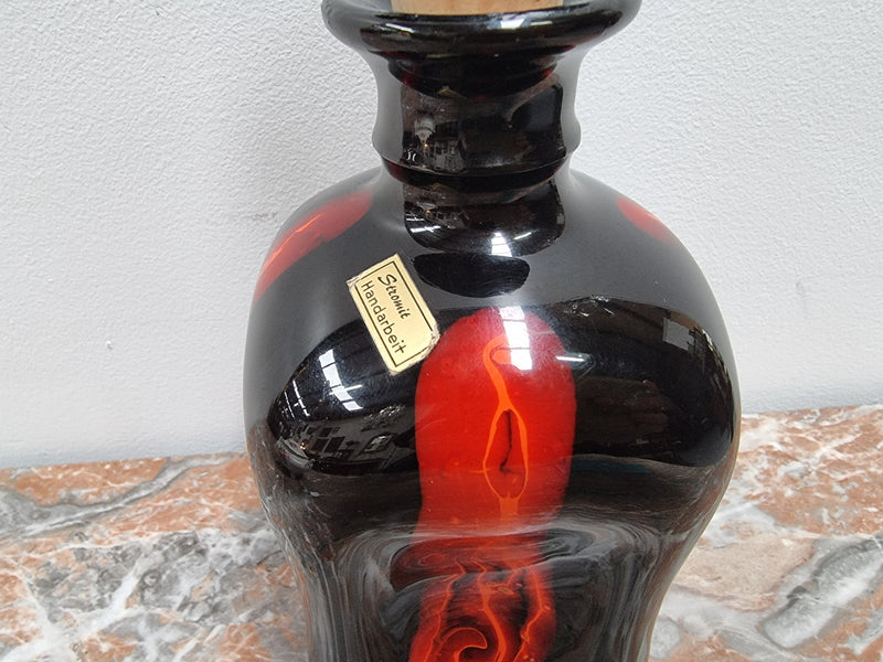 Vintage Designer glass carafe by “Stromit Handarbeit”.  Dark background with flashes of orange/red.
