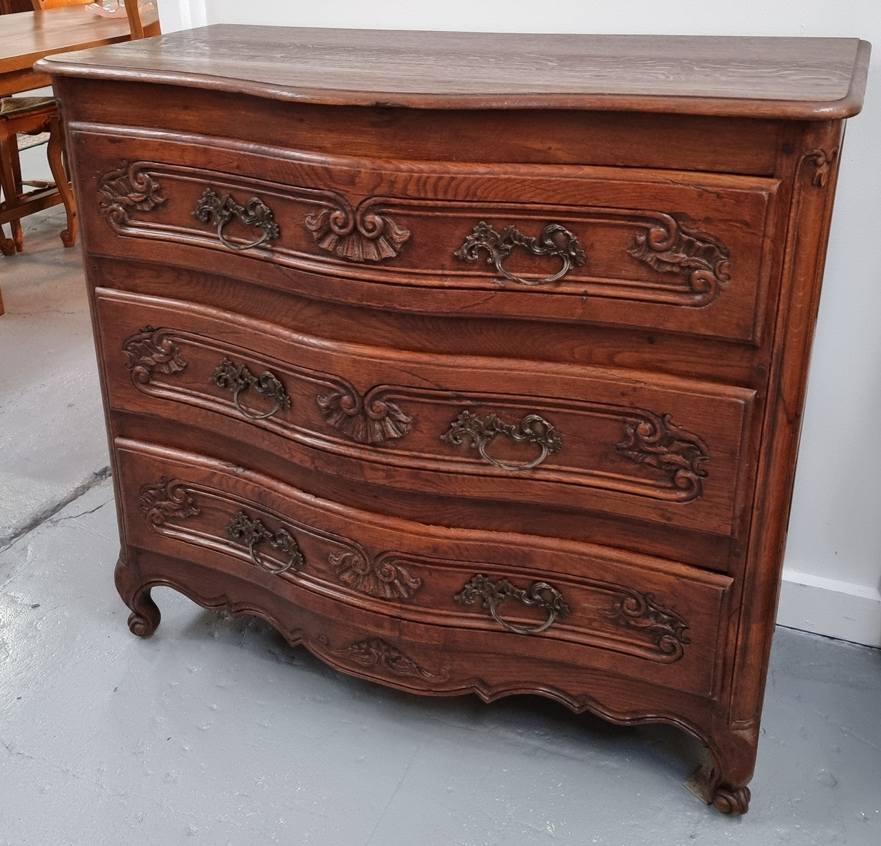 Antique French beautifully carved dark Oak commode with three drawers and ornate handles. It is in good original detailed condition.