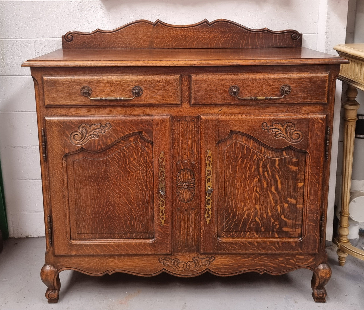 French Louis XV style Oak two door, two drawer sideboard. It is of pleasing narrow proportions and has one interior shelf. It has been sourced from France and it is in good original detailed condition.