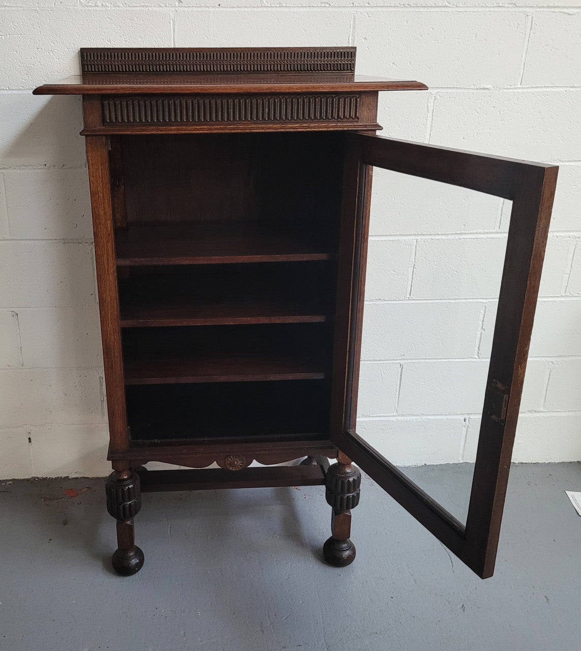 A very practical compact Oak Tudor style display cabinet with three fixed shelves. In good original detailed condition.