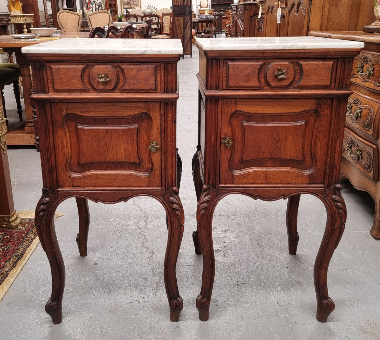 Elegant French Louis XV style pair of carved Oak white marble top bedsides. They are in good original condition and they have been detailed to a high standard. They have been sourced from France.