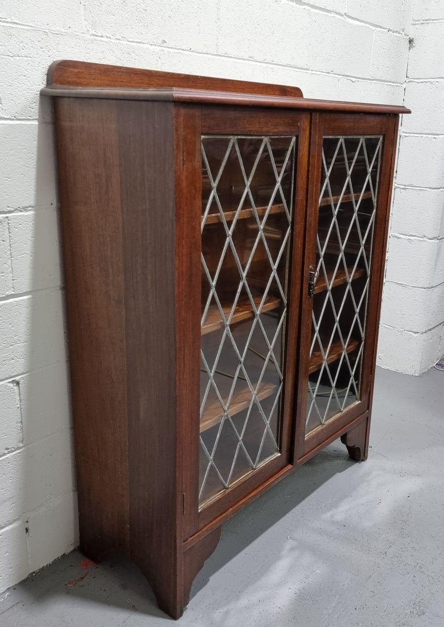 Lovely leadlight two door Oak bookcase/display cabinet with four wooden shelves. It is in good original detailed condition.
