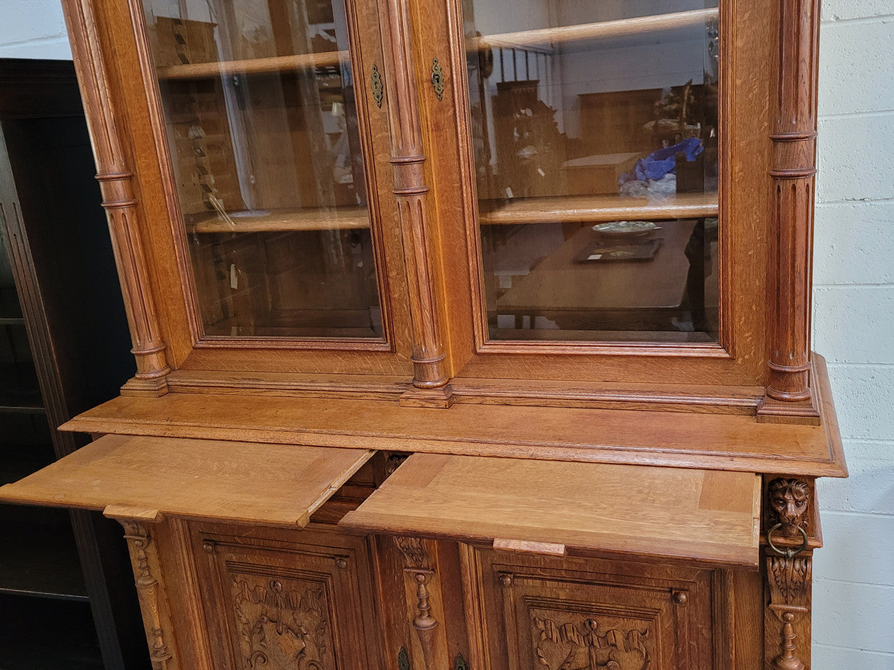 Amazing French 19th Century Oak two-door bookcase. Amazing detailed carvings throughout and plenty of storage space with three adjustable shelves at the top, two drawers, and a further shelf at the bottom. Also has two pull out reading slides giving you a large area to view your books on. In very good original detailed condition.