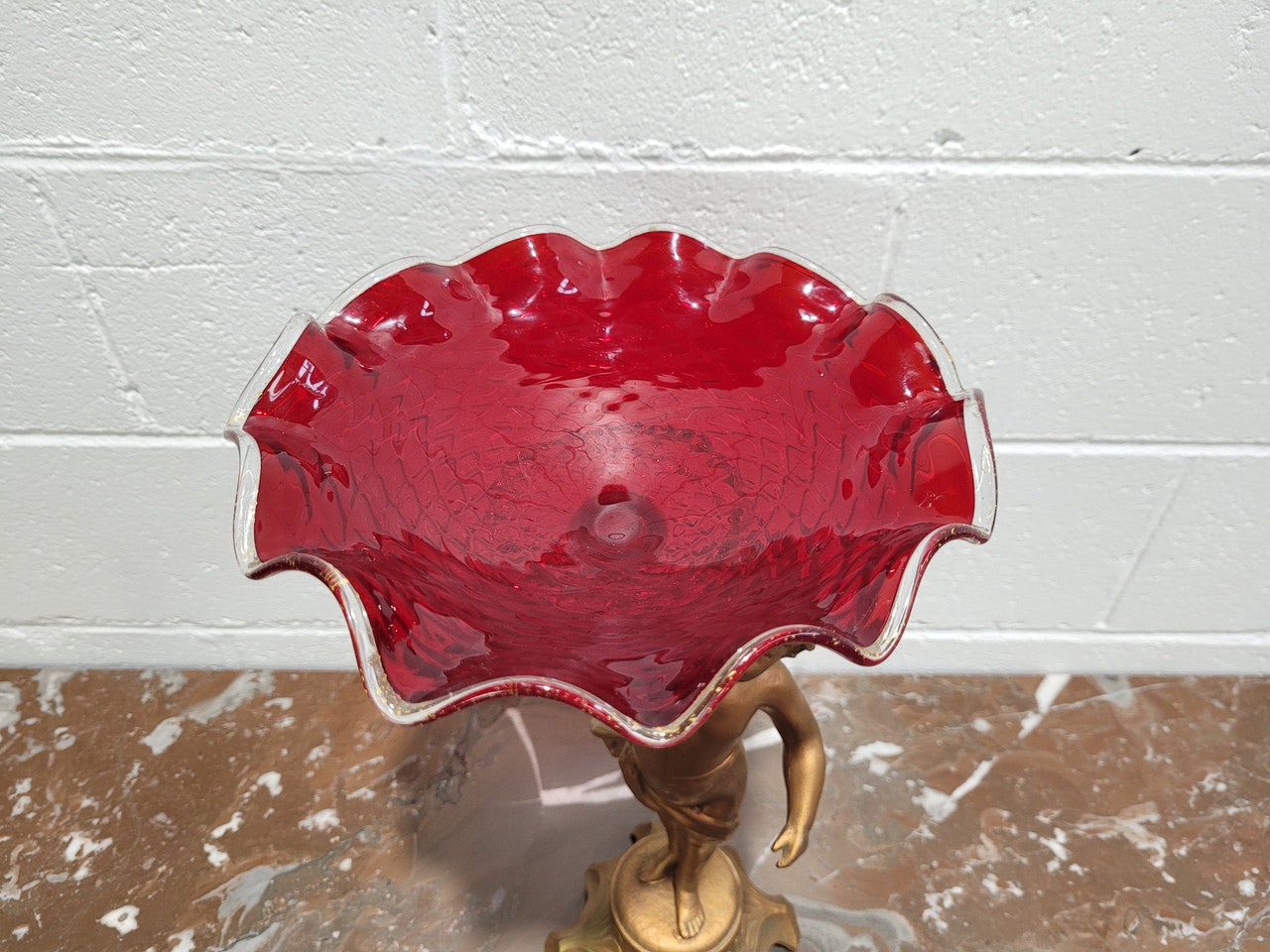 Late Victorian spelter table centerpiece/comfort featuring putti holding ruby glass bowl. In good original condition with no damage to the glass.