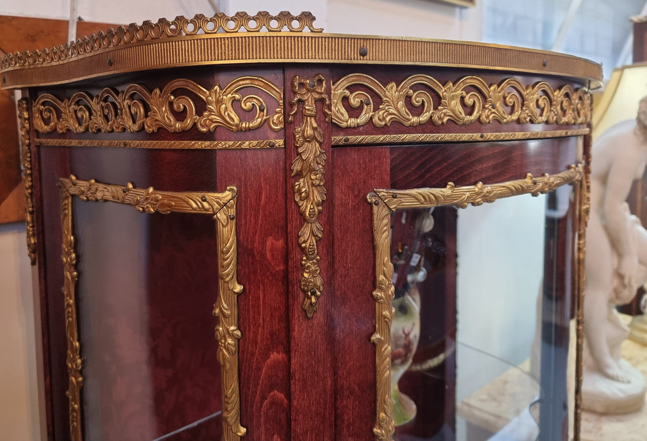 French Mahogany two shelf vitrine with curved glass and brass mounts. It has a lovely frabic interior and two glass shelves. In good original detailed condition.