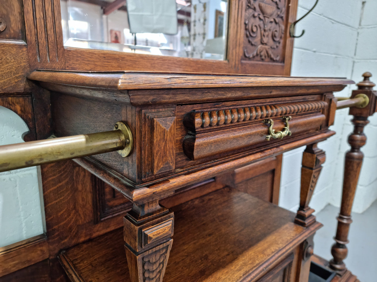 Grand Henry 2nd Style French Oak hall stand with 12 hanging hooks. Also has one cupboard and drawer for storage along with a mirror and two areas either side for umbrellas and walking sticks. In good original detailed condition.