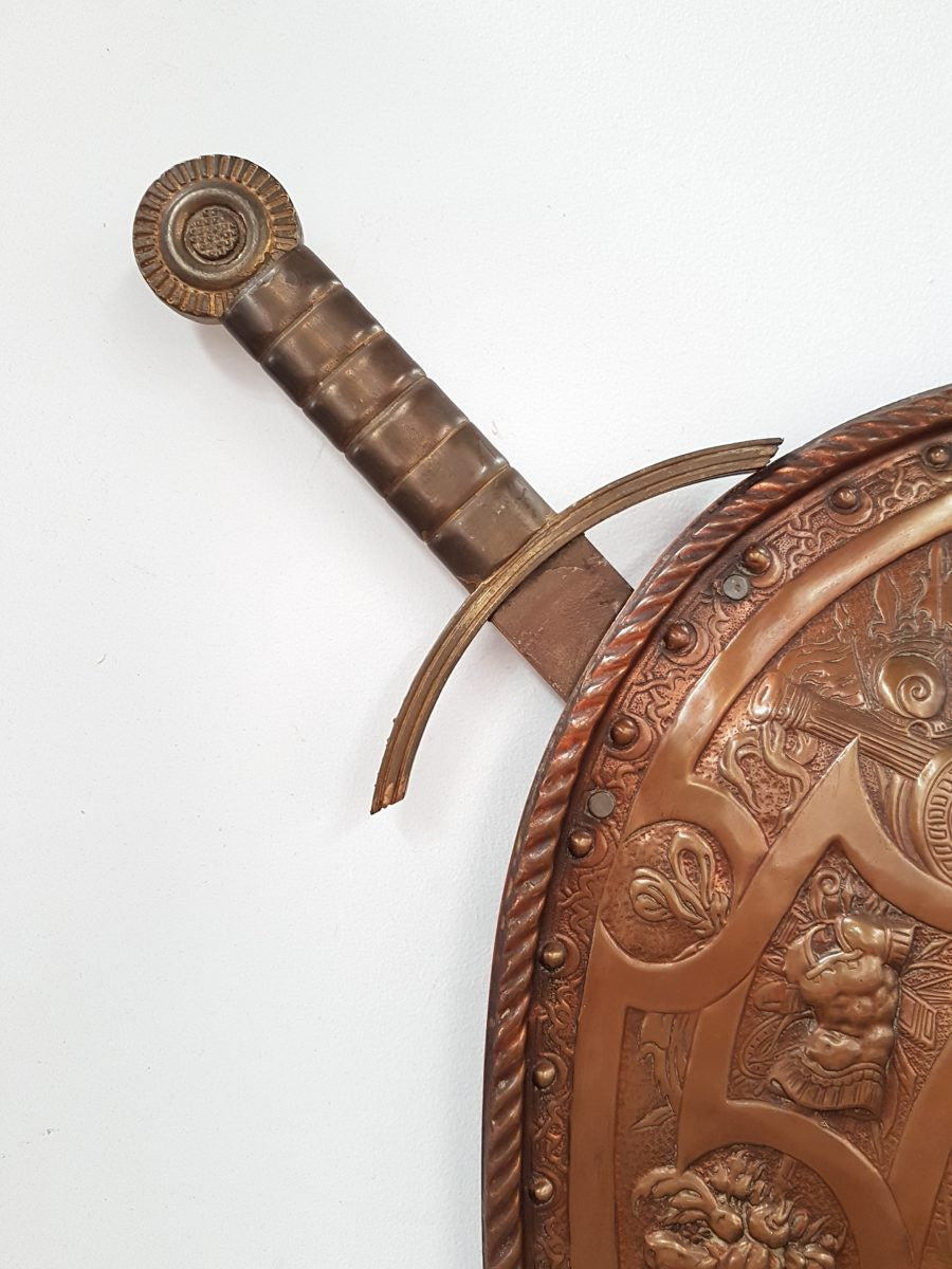 A beautiful European antique repousse copper shield, depicting a battle scene and with metal swords. It has been sourced from France and is in good original condition.