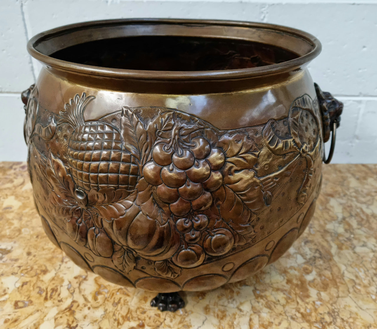 Antique large brass bronze coloured embossed Jardinière/planter with lovely details and lion heads for handles. It is in good original condition.