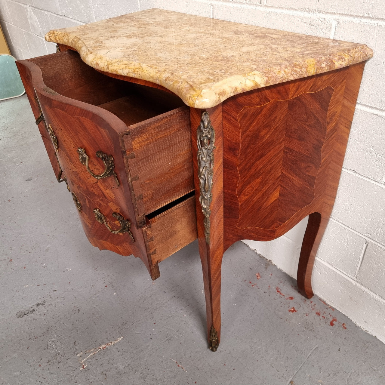 A timeless and compact French Louis XV style two drawer Kingwood marquetry inlaid commode. It features a stunning marble marble top and decorative mounts. The compact design of this commode ensures versatility, making it a perfect addition to any living space, bedroom or hallway. It has been sourced directly from France and is in good original detailed condition.