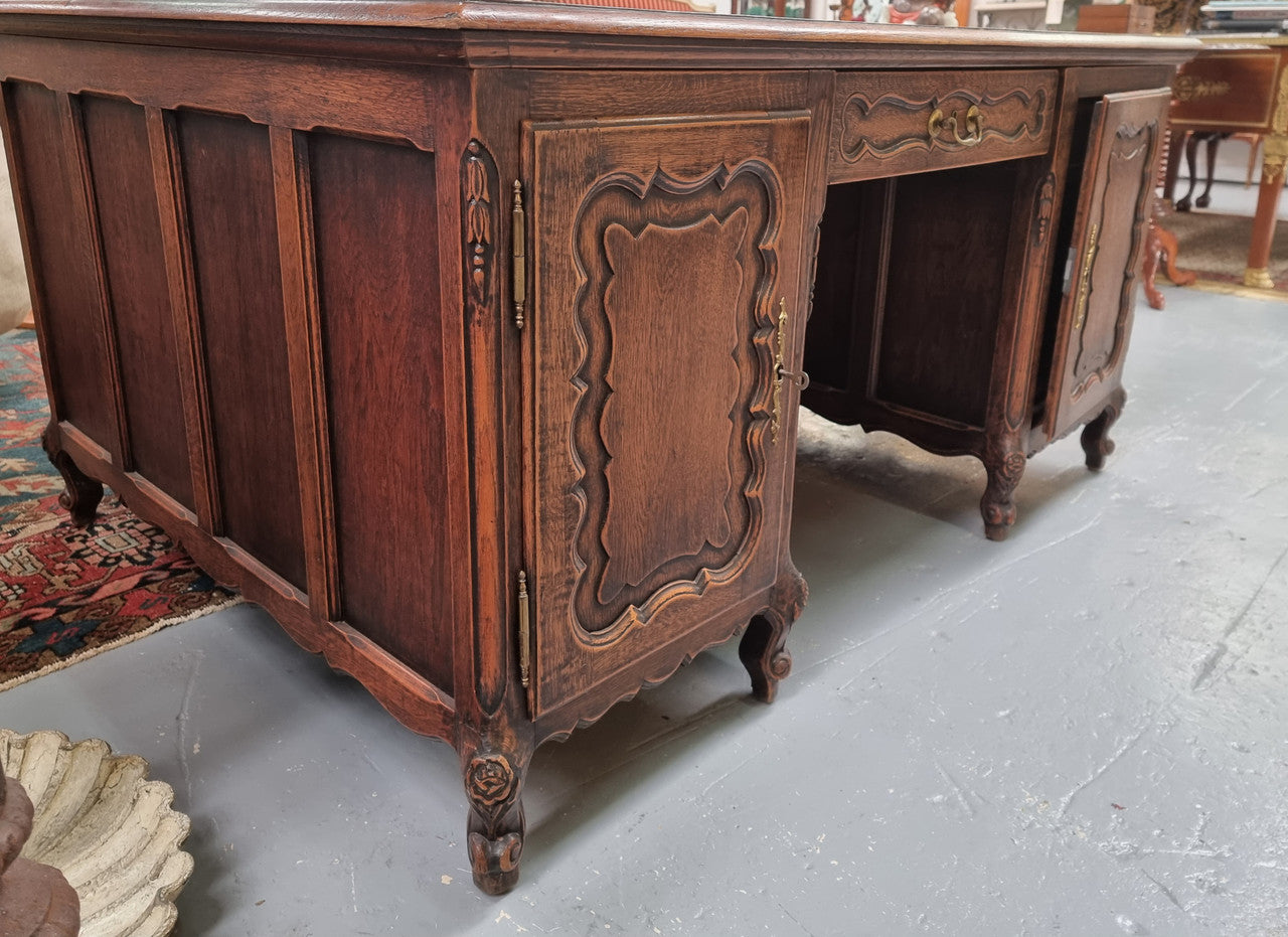 Fabulous Louis XV style French Oak beautifully carved full partners desk with an amazing tooled leather top. Both sides have a functioning drawer in the middle and two cupboards either side. On both sides one cupboard door opens up to four smaller internal drawers. Plenty of storage space and a large top surface to work on. It is in good original detailed condition.