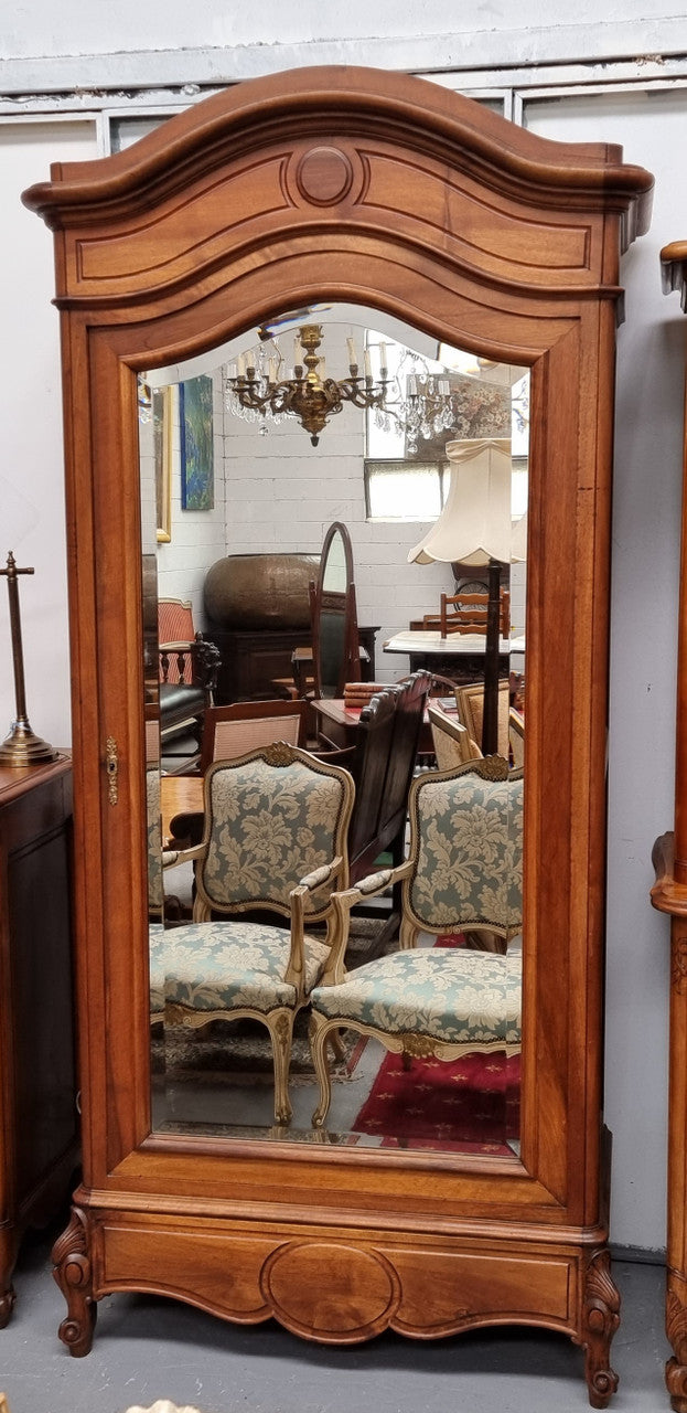 French Louis XV style Walnut armoire with single bevelled mirrored door. It has four adjustable shelves and a hidden exterior drawer at the bottom. It has been sourced from France and is in good original detailed condition.