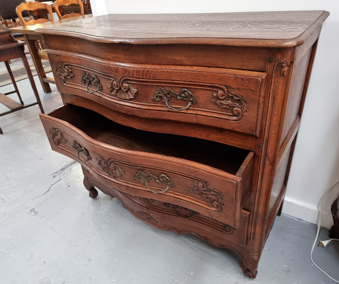 Antique French beautifully carved dark Oak commode with three drawers and ornate handles. It is in good original detailed condition.