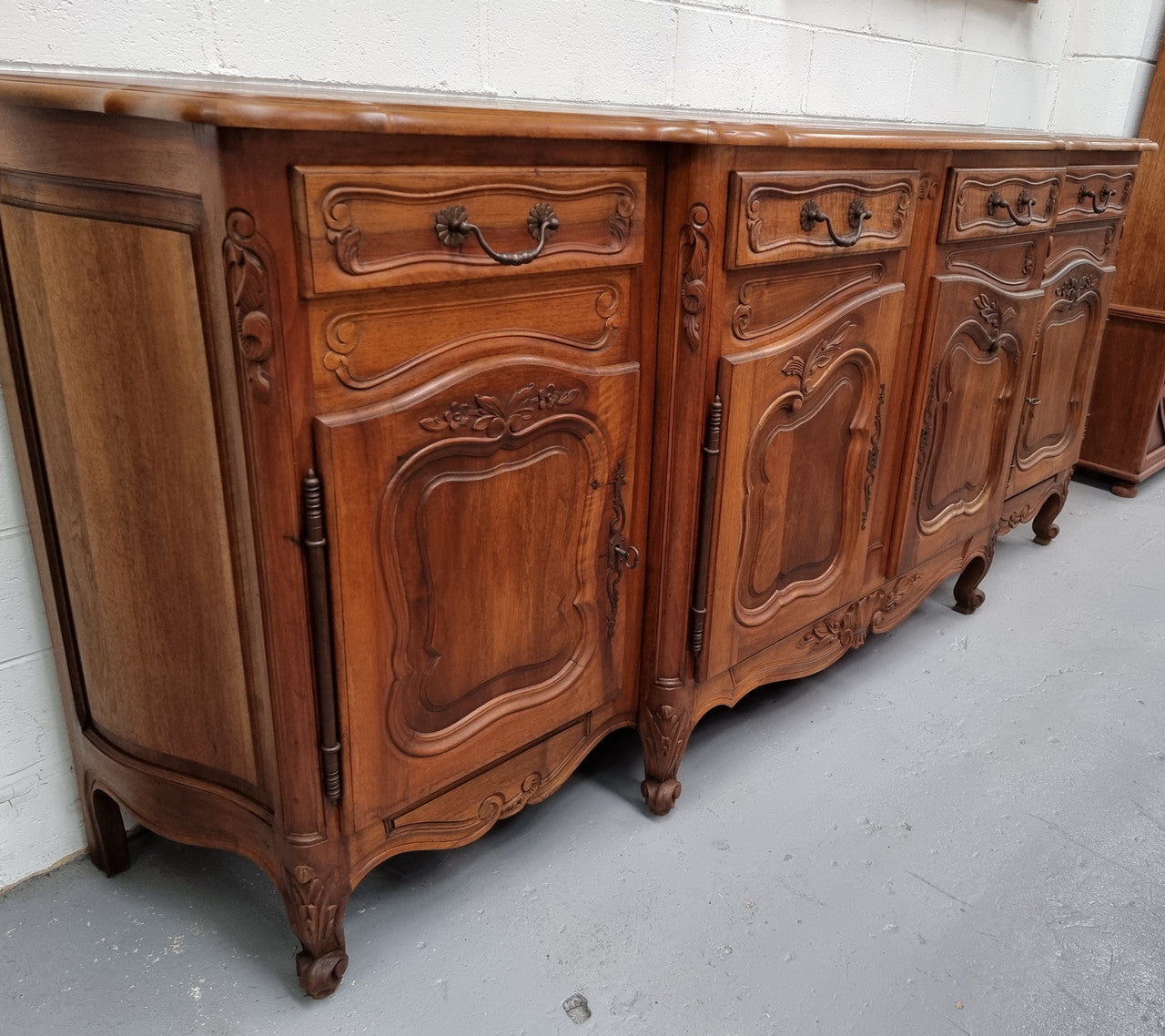 A Beautifully carved French Walnut Louis XV style four door sideboard. Plenty of storage space with four doors as well as four drawers. It is in good original detailed condition.