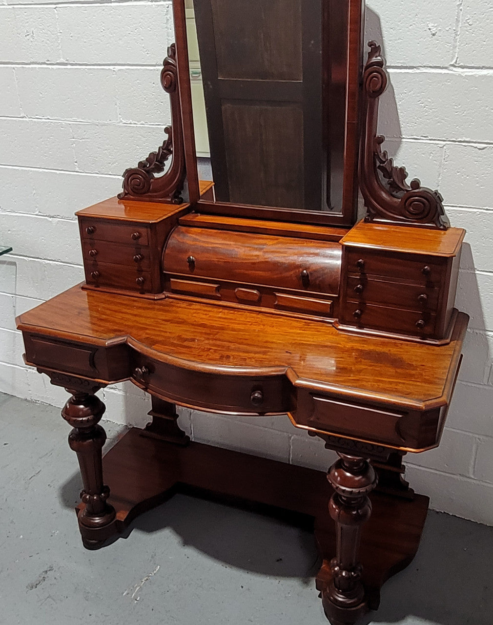 Beautiful Flame Mahogany Victorian duchess dressing table. Circa 1880 in date. It has a serpentine front outline and has an adjustable swing frame mirror. It is fitted with a central roll up storage section and then has three small drawers to either side, aswell as a central drawer in the middle of the serpentine front. It is in good original condition.