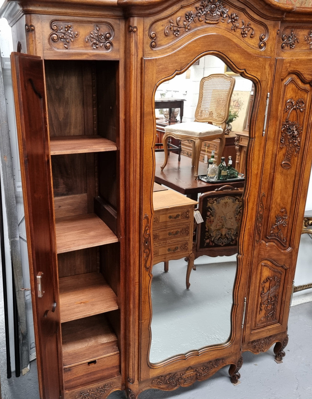French Walnut Louis XV style three door armoire with 10 fully adjustable shelves in total spread over three sections, two drawers and a mirrored middle door. It has been sourced from France and in good original detailed condition.