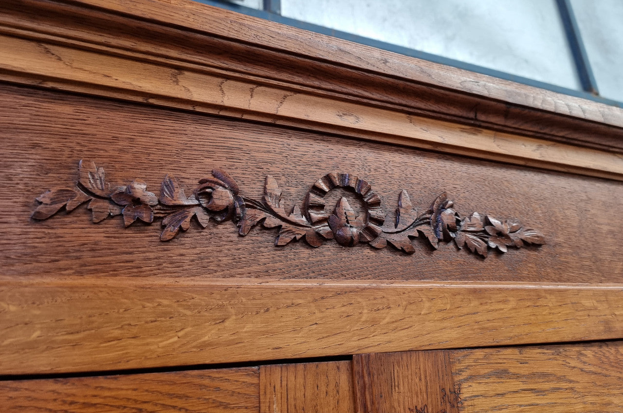 French light Oak two door bookcase with four adjustable shelves. It has beautiful decorative carving and is in good original detailed condition.