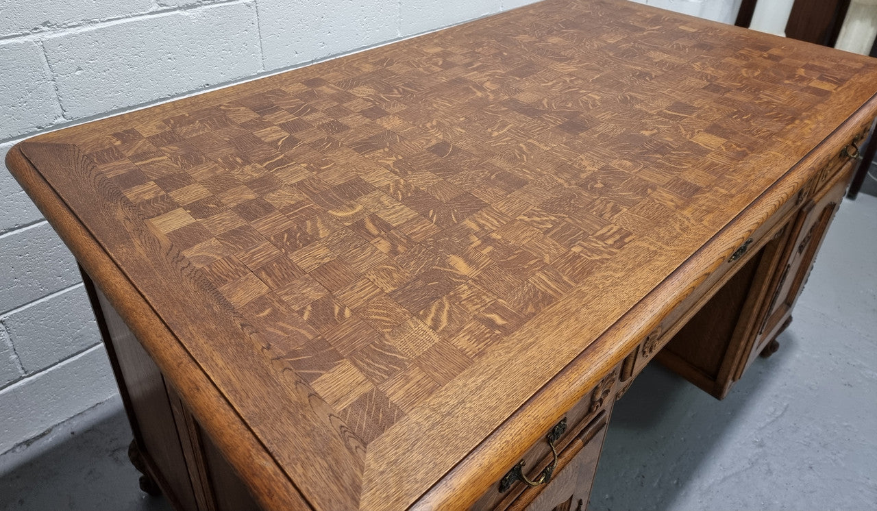 Fabulous French oak carved partners desk with a lovely parquetry top. It has three drawers and two cupboards on one side and two cupboards on the other side with no functioning drawers. It is in good original detailed condition.