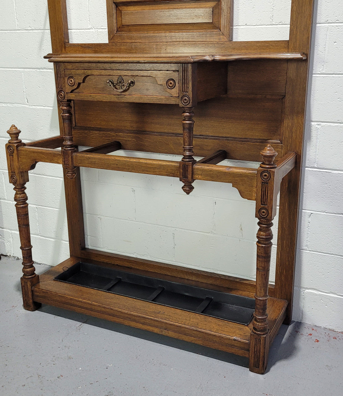 Impressive Oak hall stand of grand portions. Plenty of storage with a drawer, plenty of hooks and two sections for umbrealls/ walking sticks. It is in good original detailed condition.