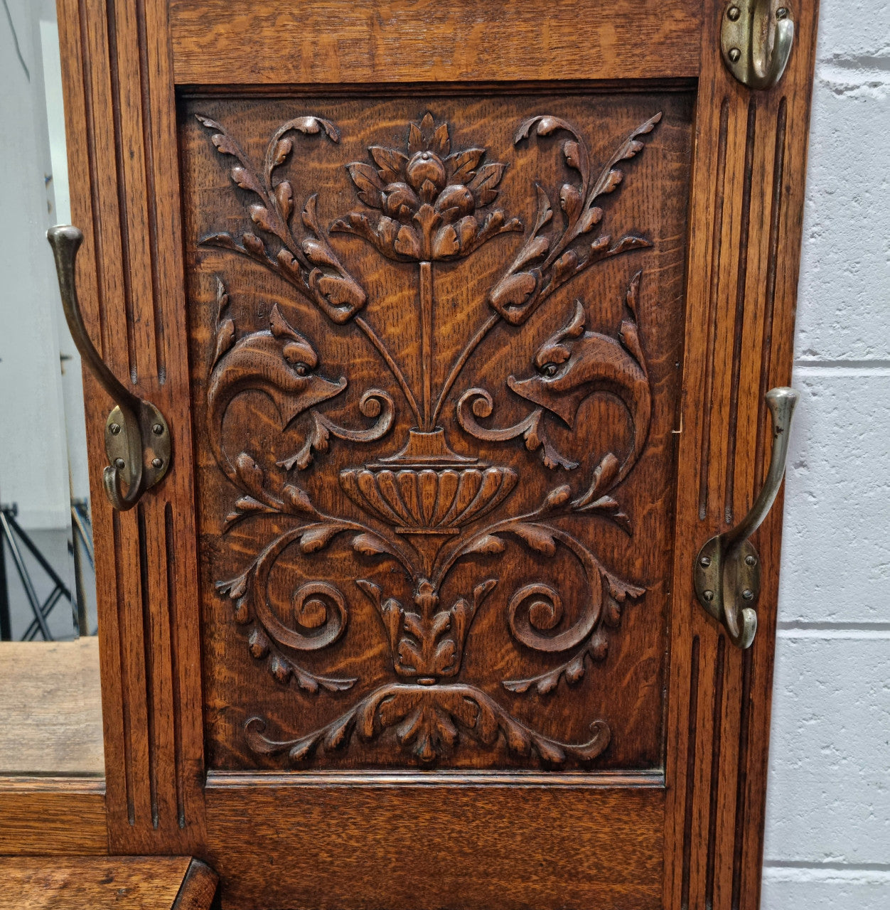 Grand Henry 2nd Style French Oak hall stand with 12 hanging hooks. Also has one cupboard and drawer for storage along with a mirror and two areas either side for umbrellas and walking sticks. In good original detailed condition.
