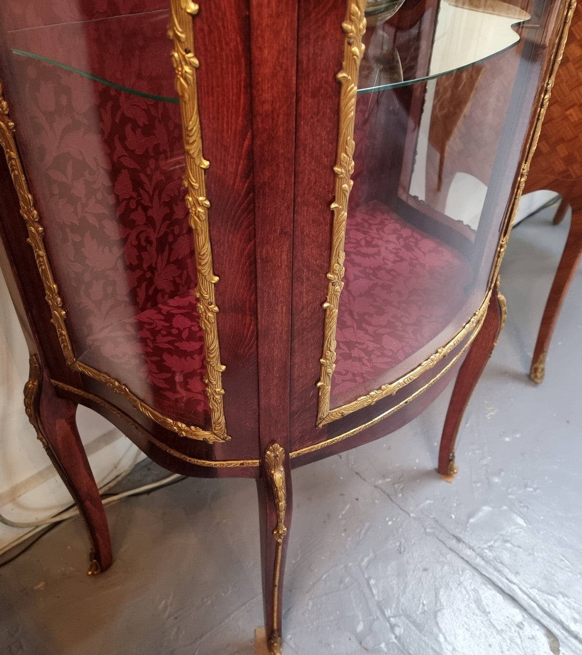 French Mahogany two shelf vitrine with curved glass and brass mounts. It has a lovely frabic interior and two glass shelves. In good original detailed condition.