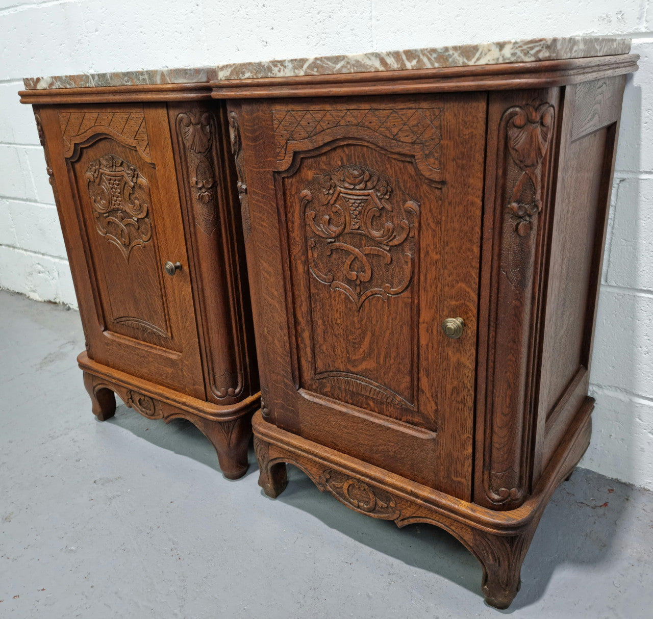 Lovely pair of French oak bedside cabinets with nicely carved details and marble tops. In good original detailed condition.