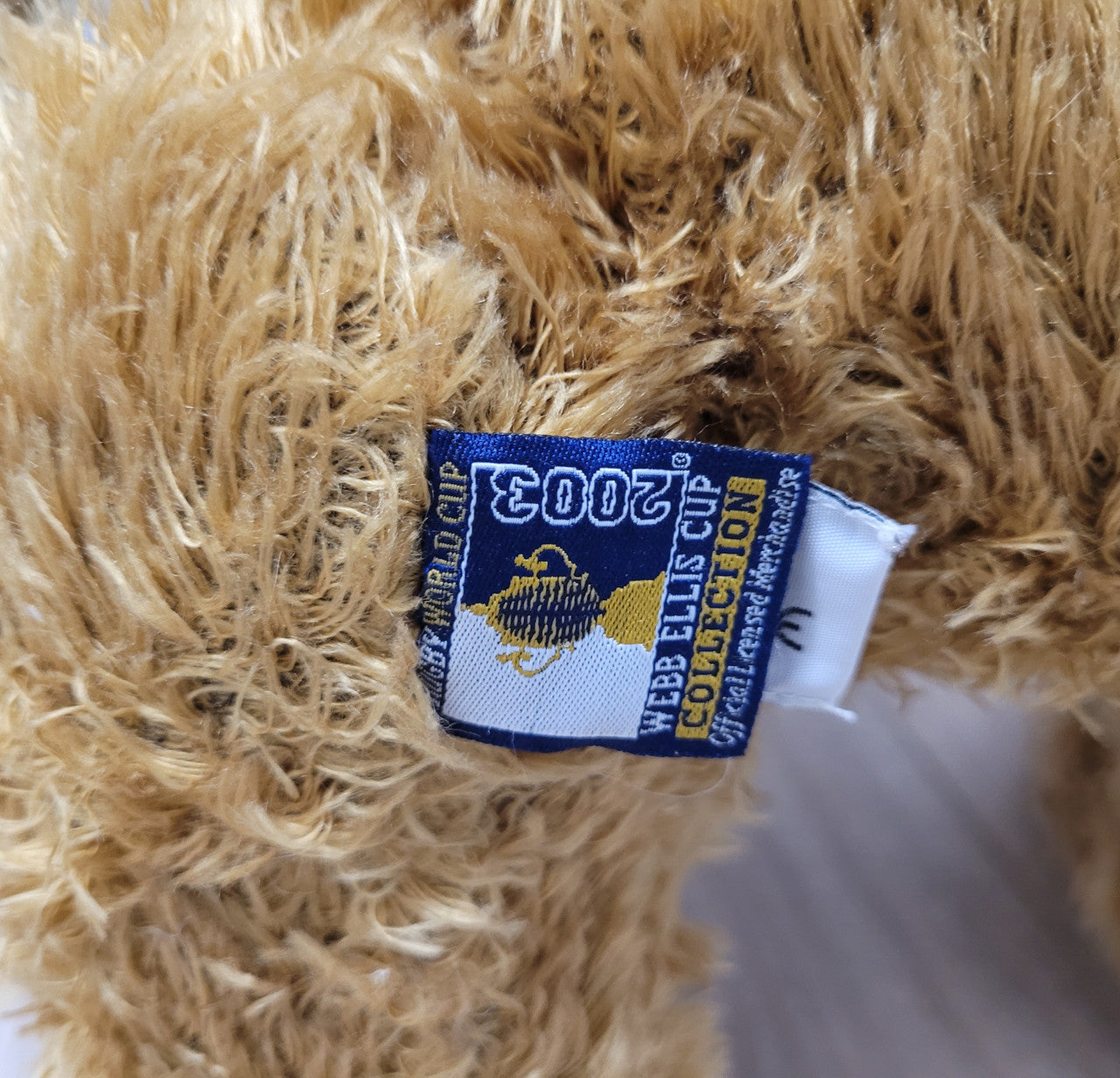 World Cup Rugby Bear. William by RUSS a special release for 2003. Limited to 5000 pieces worldwide. 50.8 cm fully jointed golden-brown bear with suedeen paw pads and blue scarf with Rugby World Cup Logo embroidery.
*Please note chair in photo is not included.