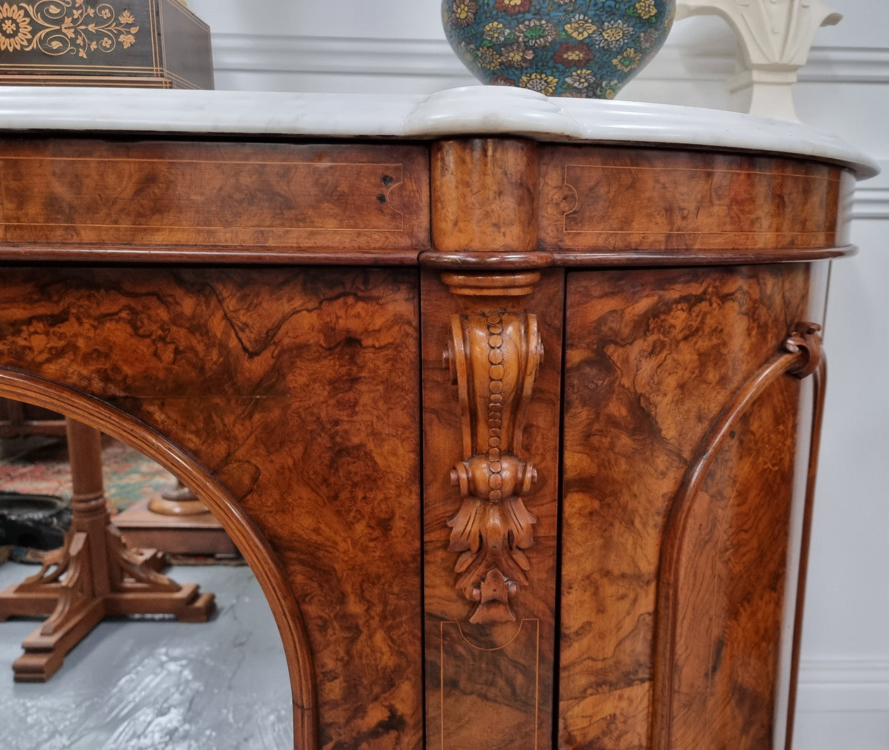 An elegant Antique Victorian Burr wood Walnut marble-top sideboard credenza with a mirrored center door. It has a white shaped marble top, mirror front, nicely carved details and three swing doors along with two keys. It is in good original detailed condition.