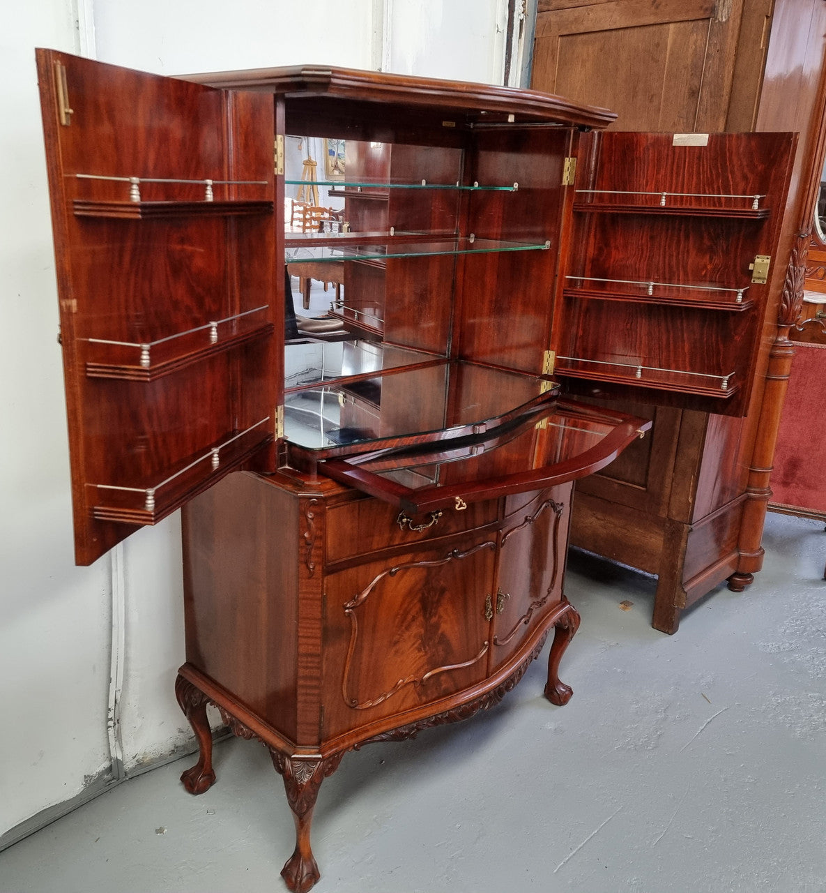 1950’s Chippendale Style Flame Mahogany Four door Bar. The top section has glass shelves and a mirrored pull out tray for storing glasses, decanters & serving etc. It also has a silver presentation plaque to the Mayor of Hawthorn 1958. The bottom section is for storage bottles etc. A stunning and practical piece.