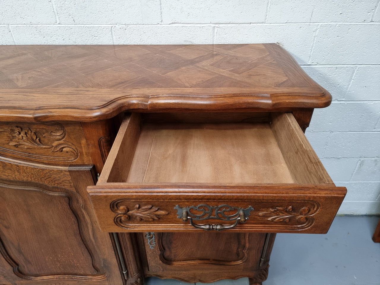Parquetry top French oak Louis XV style sideboard with two draws and four cupboards. In good original detailed condition.