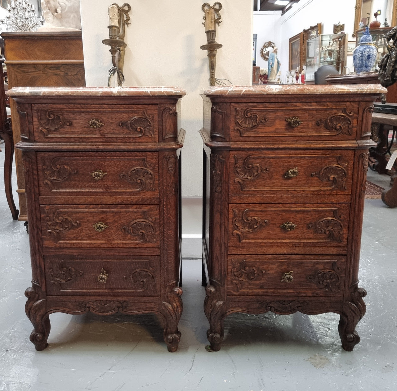 A pair of hard to find French Oak Louis XV style four drawer marble topped bedsides with attractive carvings. They are in good original detailed condition and have been sourced from France.