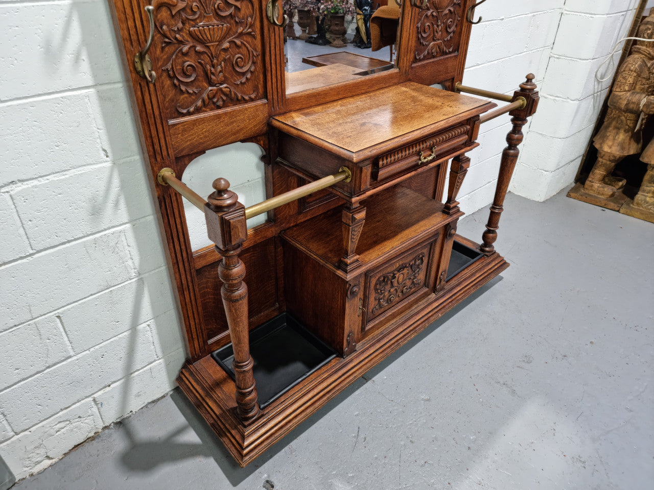 Grand Henry 2nd Style French Oak hall stand with 12 hanging hooks. Also has one cupboard and drawer for storage along with a mirror and two areas either side for umbrellas and walking sticks. In good original detailed condition.