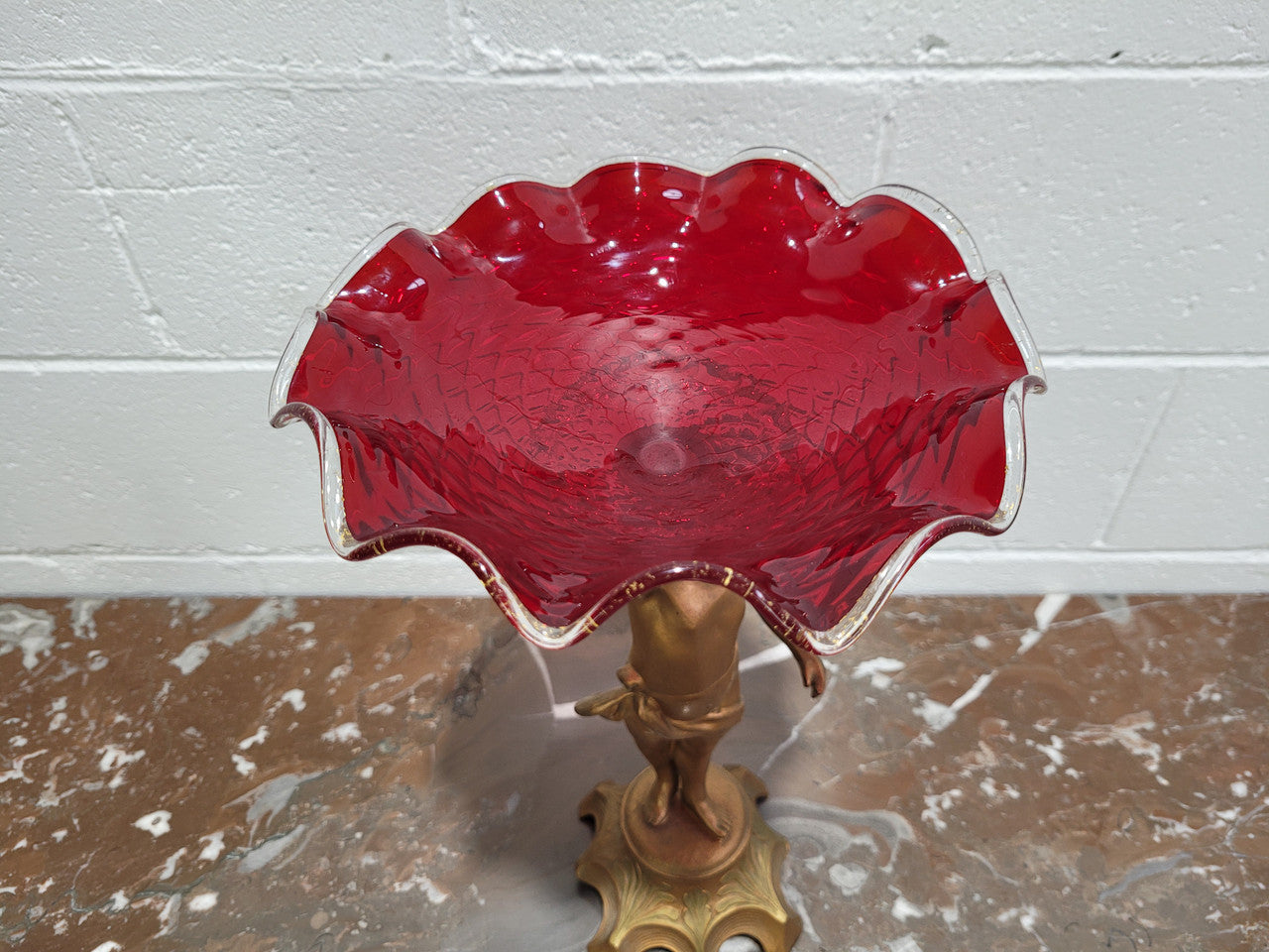 Late Victorian spelter table centerpiece/comfort featuring putti holding ruby glass bowl. In good original condition with no damage to the glass.
