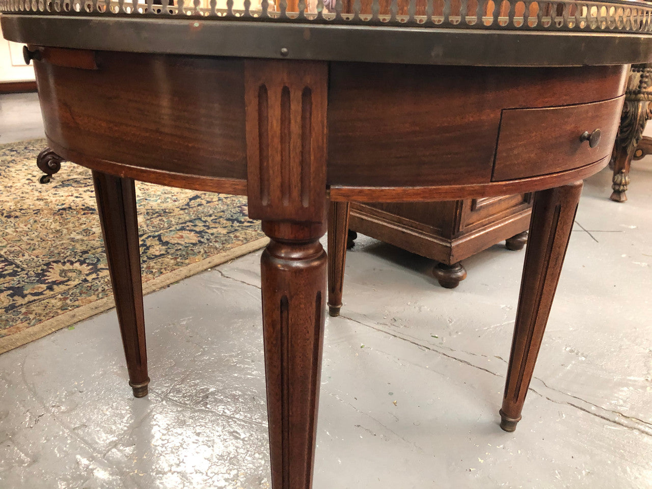 Large French Bouillotte table with a marble top and brass fitted gallery. It has two concealed leather - topped slides and two drawers and in good original condition.