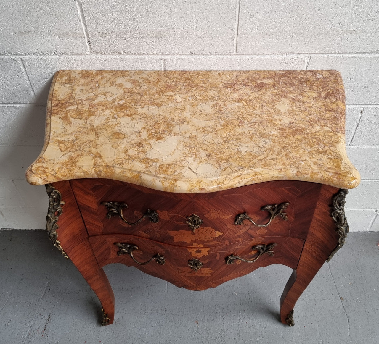 A timeless and compact French Louis XV style two drawer Kingwood marquetry inlaid commode. It features a stunning marble marble top and decorative mounts. The compact design of this commode ensures versatility, making it a perfect addition to any living space, bedroom or hallway. It has been sourced directly from France and is in good original detailed condition.