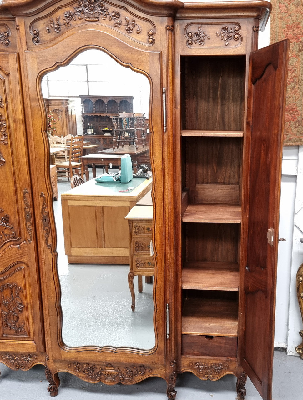 French Walnut Louis XV style three door armoire with 10 fully adjustable shelves in total spread over three sections, two drawers and a mirrored middle door. It has been sourced from France and in good original detailed condition.