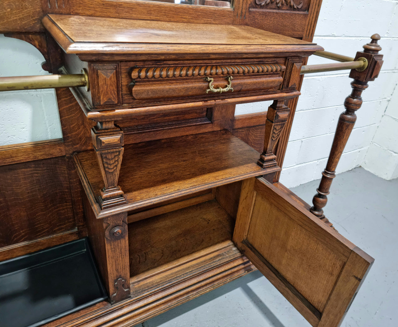 Grand Henry 2nd Style French Oak hall stand with 12 hanging hooks. Also has one cupboard and drawer for storage along with a mirror and two areas either side for umbrellas and walking sticks. In good original detailed condition.