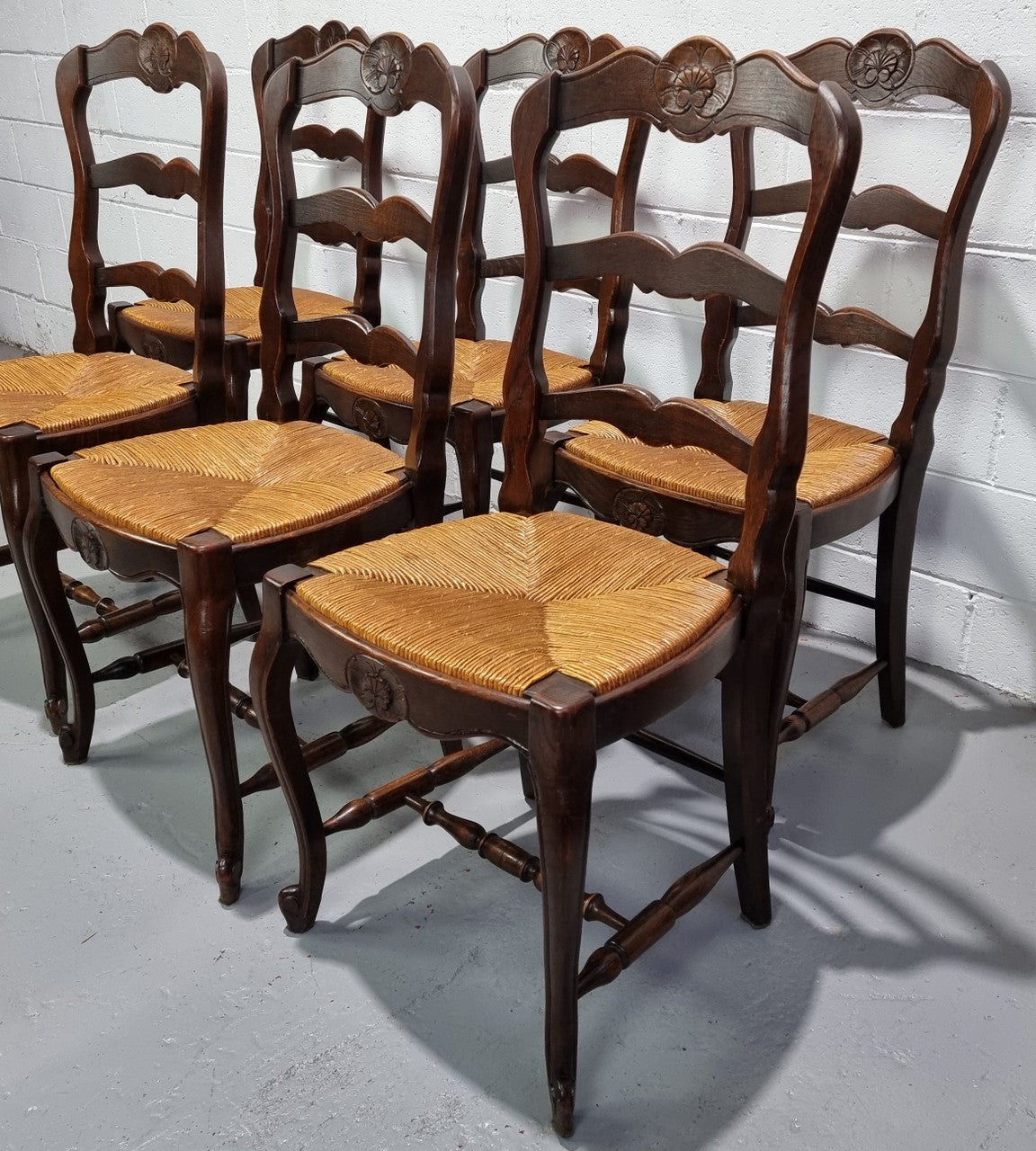 Set of six French dark Oak rush seat dining chairs with ladder back. They are in good detailed original condition and very comfortable to sit in.
