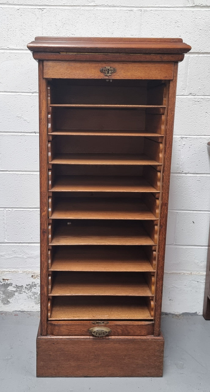 Antique Edwardian roll top Tambour file cabinet desk. This practical antique tambour front filing cabinet dates around 1900 in the Edwardian period and is constructed from Oak. This antique cabinet has an adjustable writing slope, above a tambour front with key and working lock. It has been sourced locally and is in good original detailed condition.