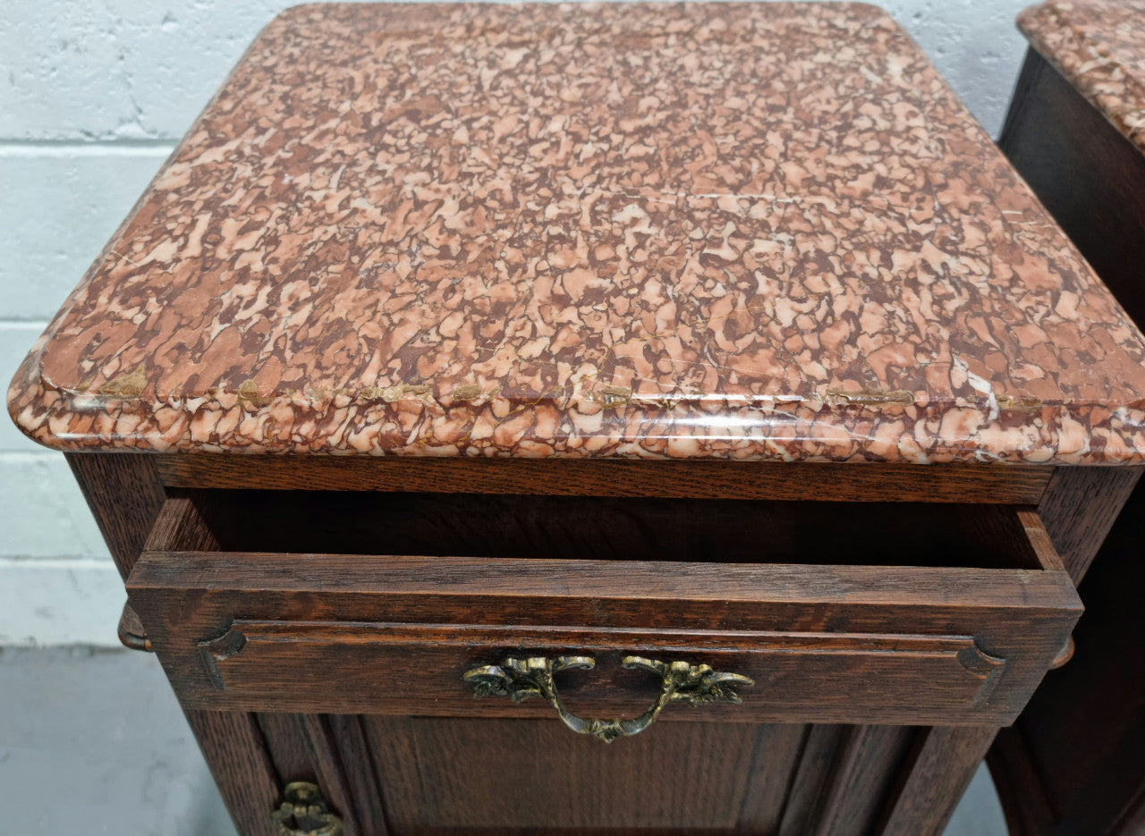 Stunning pair of French dark Oak bedside cabinets with a beautiful coloured marble top. They have one drawer and cupboard. They are in good original detailed condition.