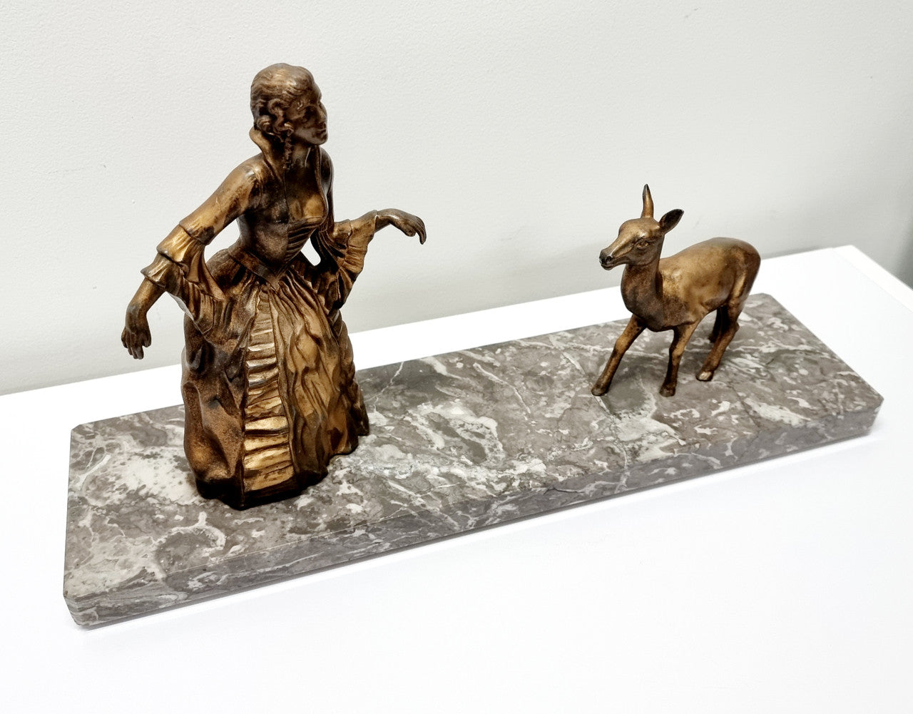 Art Deco gilt metal lady and deer statue on a lovely grey marble base. It has been sourced from France and is in good original condition. The marble does have some minor chips and wear due to age, please view photos as they help form part of the description. Please contact us if you would like additional photos.