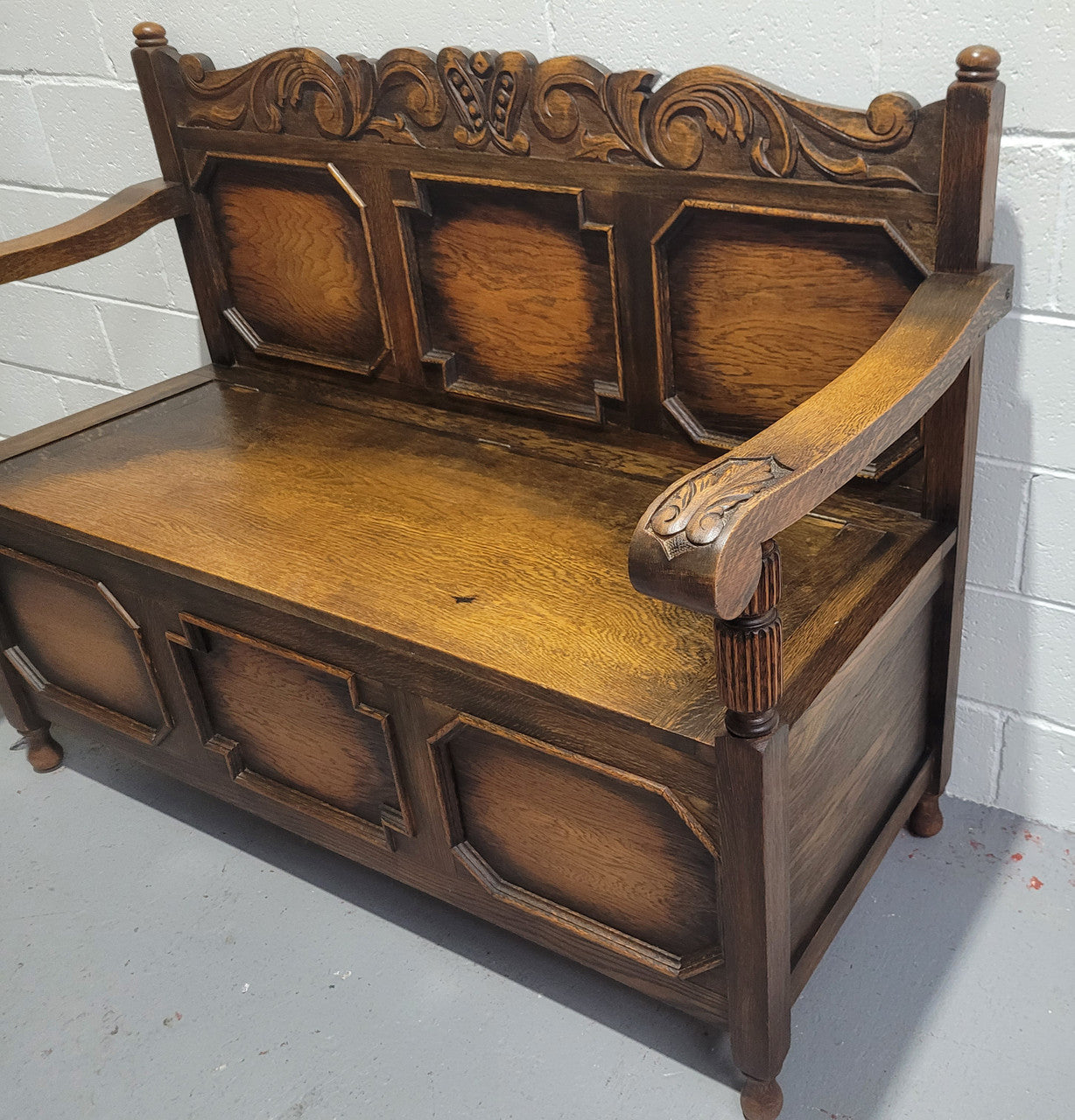 English Oak Tudor style hall seat with lift up top and a storage compartment underneath. It is in good original detailed condition with its original finish.