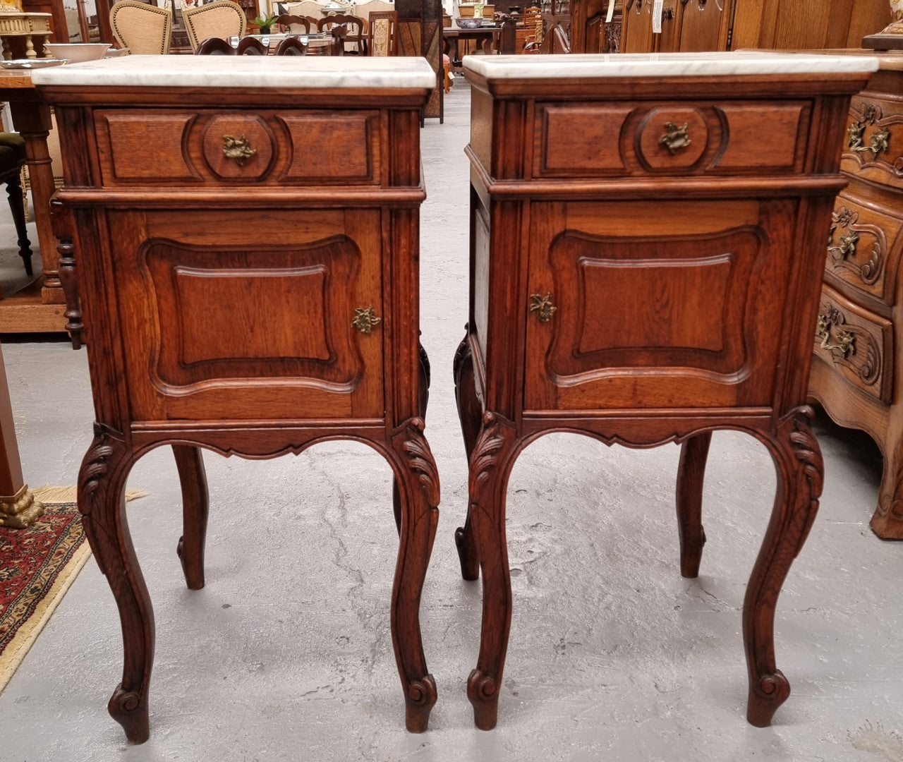 Elegant French Louis XV style pair of carved Oak white marble top bedsides. They are in good original condition and they have been detailed to a high standard. They have been sourced from France.