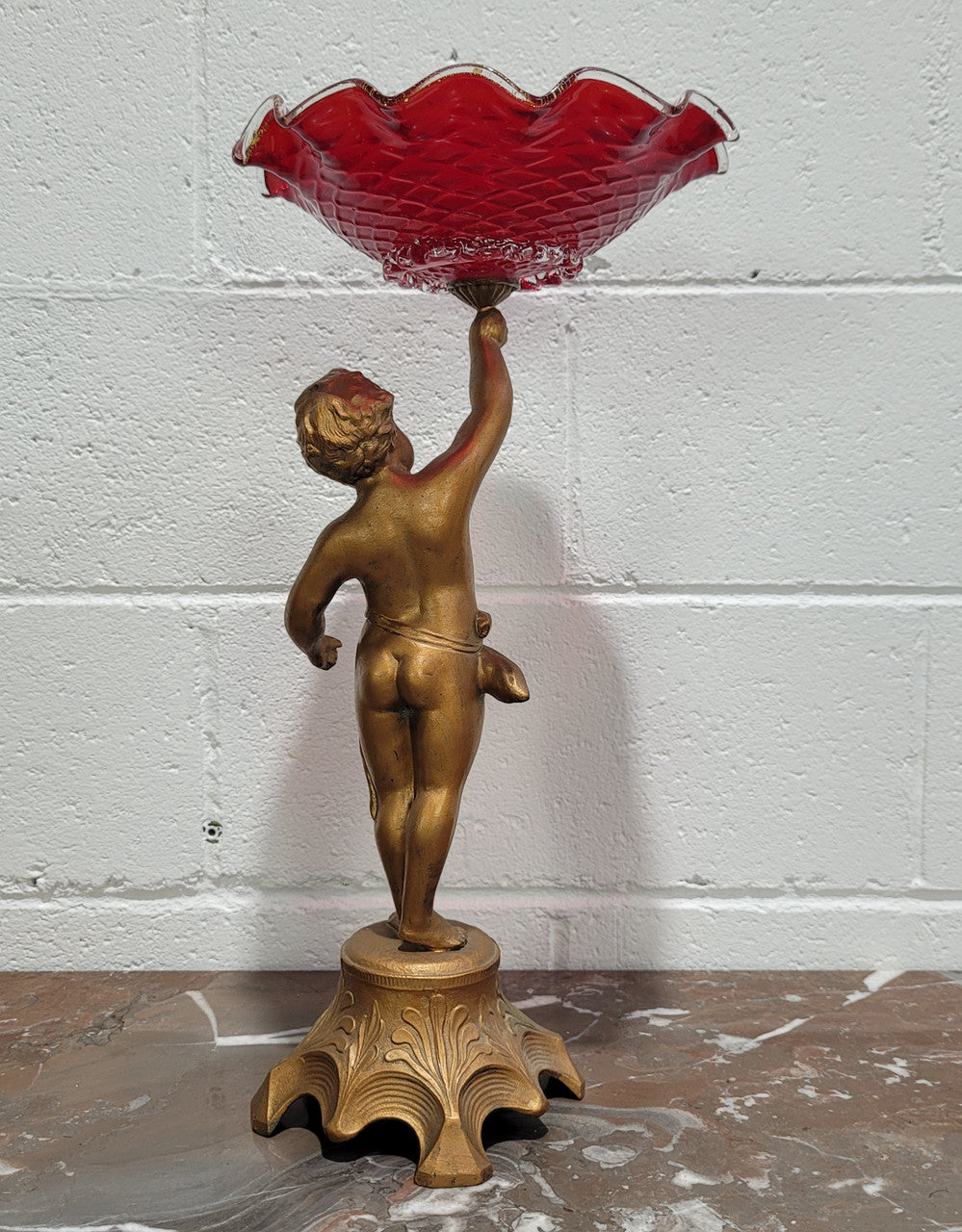 Late Victorian spelter table centerpiece/comfort featuring putti holding ruby glass bowl. In good original condition with no damage to the glass.