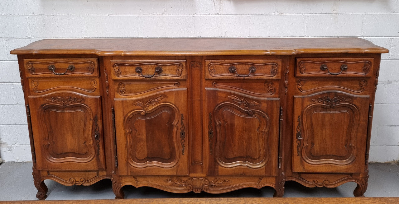 A Beautifully carved French Walnut Louis XV style four door sideboard. Plenty of storage space with four doors as well as four drawers. It is in good original detailed condition.