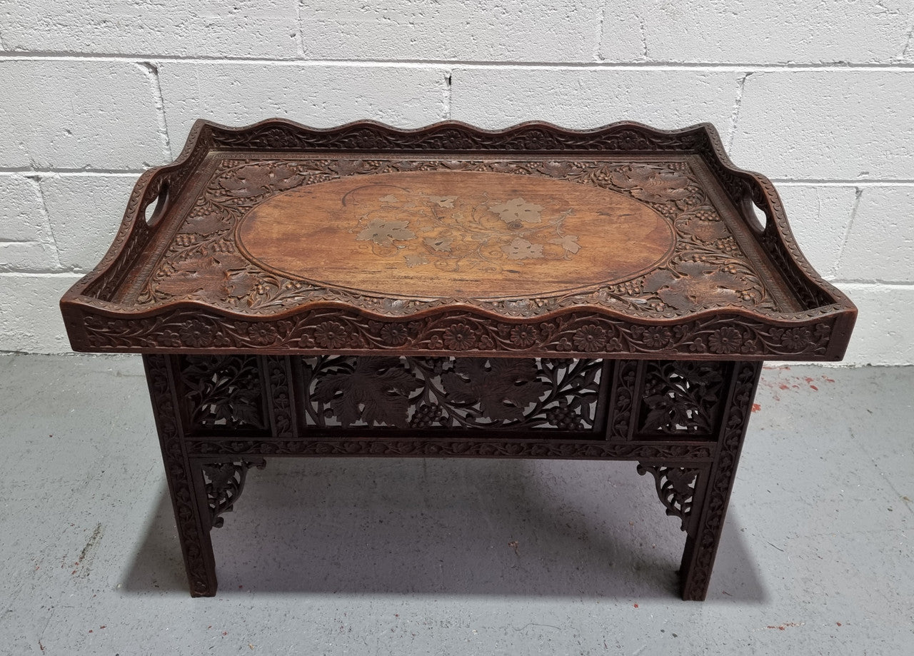 Anglo Indian folding occasional table with lift-up tray top. The tray has brass inlay and ornate carvings. The bottom of the table folds down and it is in good original condition.