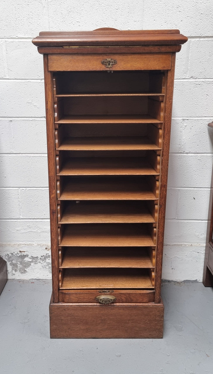 Antique Edwardian roll top Tambour file cabinet desk. This practical antique tambour front filing cabinet dates around 1900 in the Edwardian period and is constructed from Oak. This antique cabinet has an adjustable writing slope, above a tambour front with key and working lock. It has been sourced locally and is in good original detailed condition.