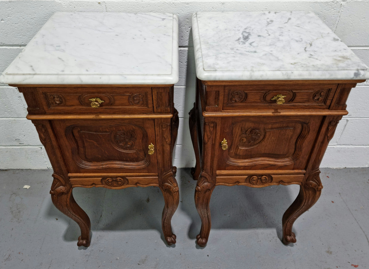Lovely pair of French Oak carved Louis XV style bedside cabinets with a white marble top, drawer and cupboard in good original detailed condition.